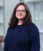 smiling woman with glasses and dark shirt