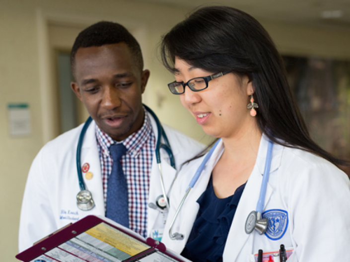 Two CWRU medical students in white coats in discussion on a clinical rotation