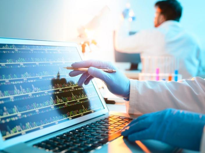 A lab tech looking at a screen with DNA Sequencing