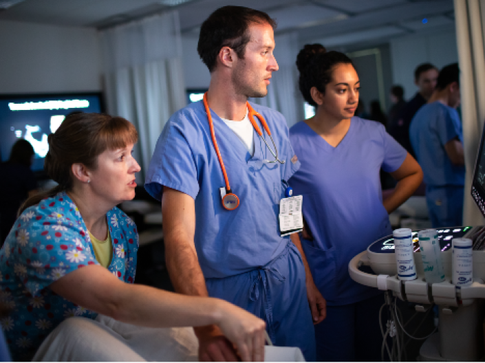 Three medical professionals looking at a monitor