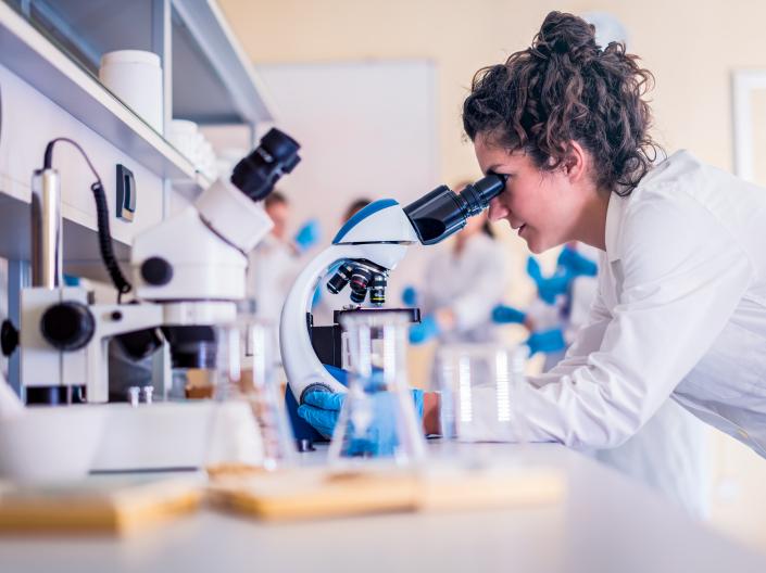 Female scientist looking through microscope