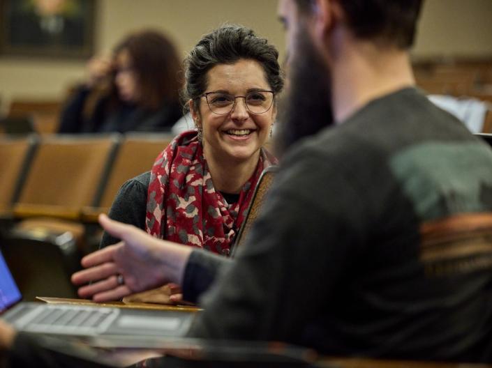 A professor smiling while talking with one of her students.