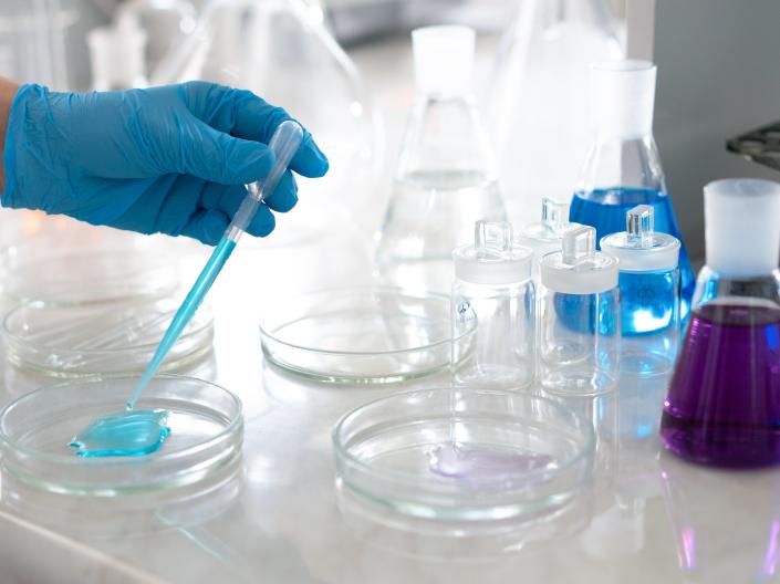 A person performing an experiment using scientific beakers and pipettes.