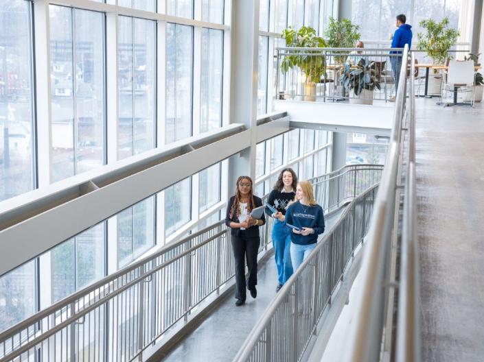 Three women talk as they walk up a stairwell together