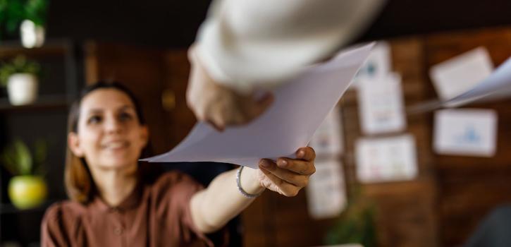 Two coworkers exchanging a grant document