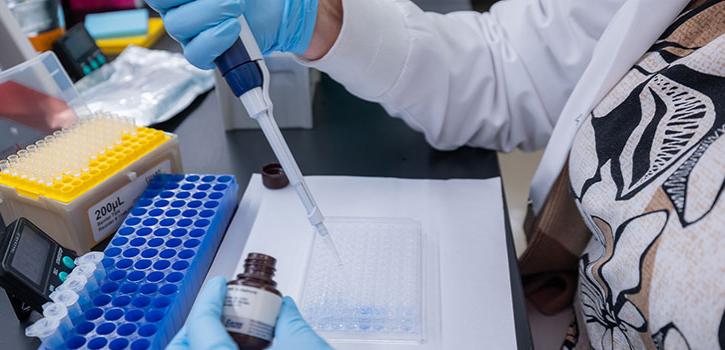 Hand using a pipette to transfer substance to a container