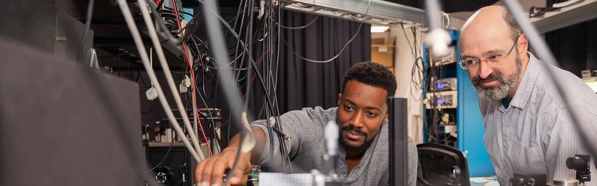 A professor and research assistant in a lab looking at a piece of research equipment