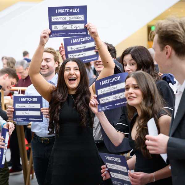 A CWRU School of Medicine student holds up a sign reading “I Matched” while other students hold signs around them and celebrate.