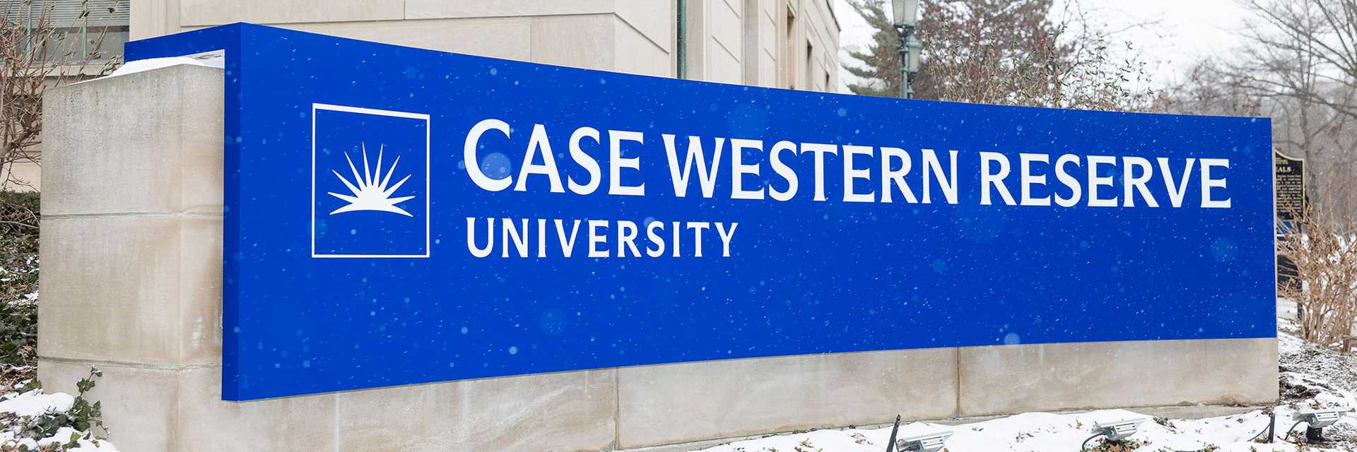 Photo of a stone sign on campus with the Case Western Reserve University logo, with flowers beneath