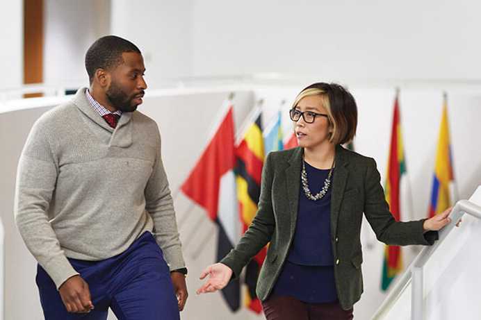 Photo of a Case Western Reserve University student and faculty member walking up stairs and talking inside Peter B. Lewis building