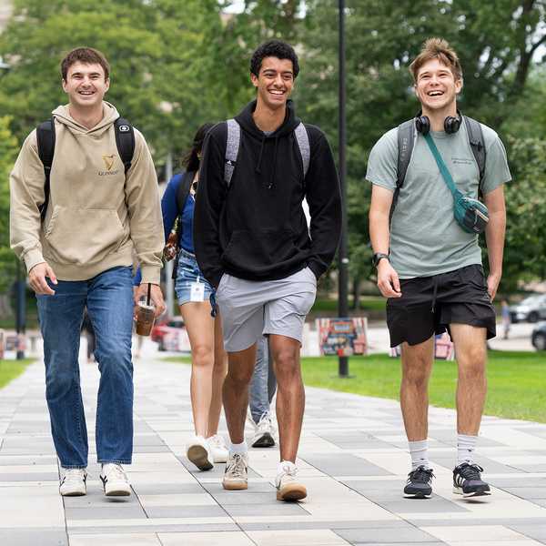Three CWRU students walking and smiling on Binary Walkway.
