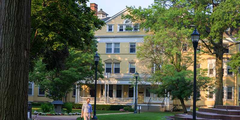 Photo of Guilford House on Mather Quad at Case Western Reserve University, with a student walking in front on sidewalk