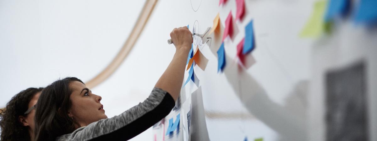 Image of a participant writing on a white board covered in post its